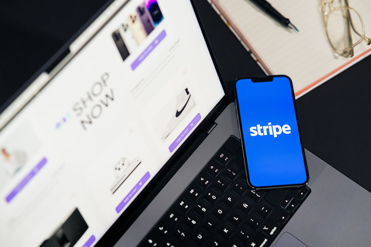 Services-03 Mobile phone showing the Stripe app on a laptop beside an eCommerce website open, illustrating online shopping.